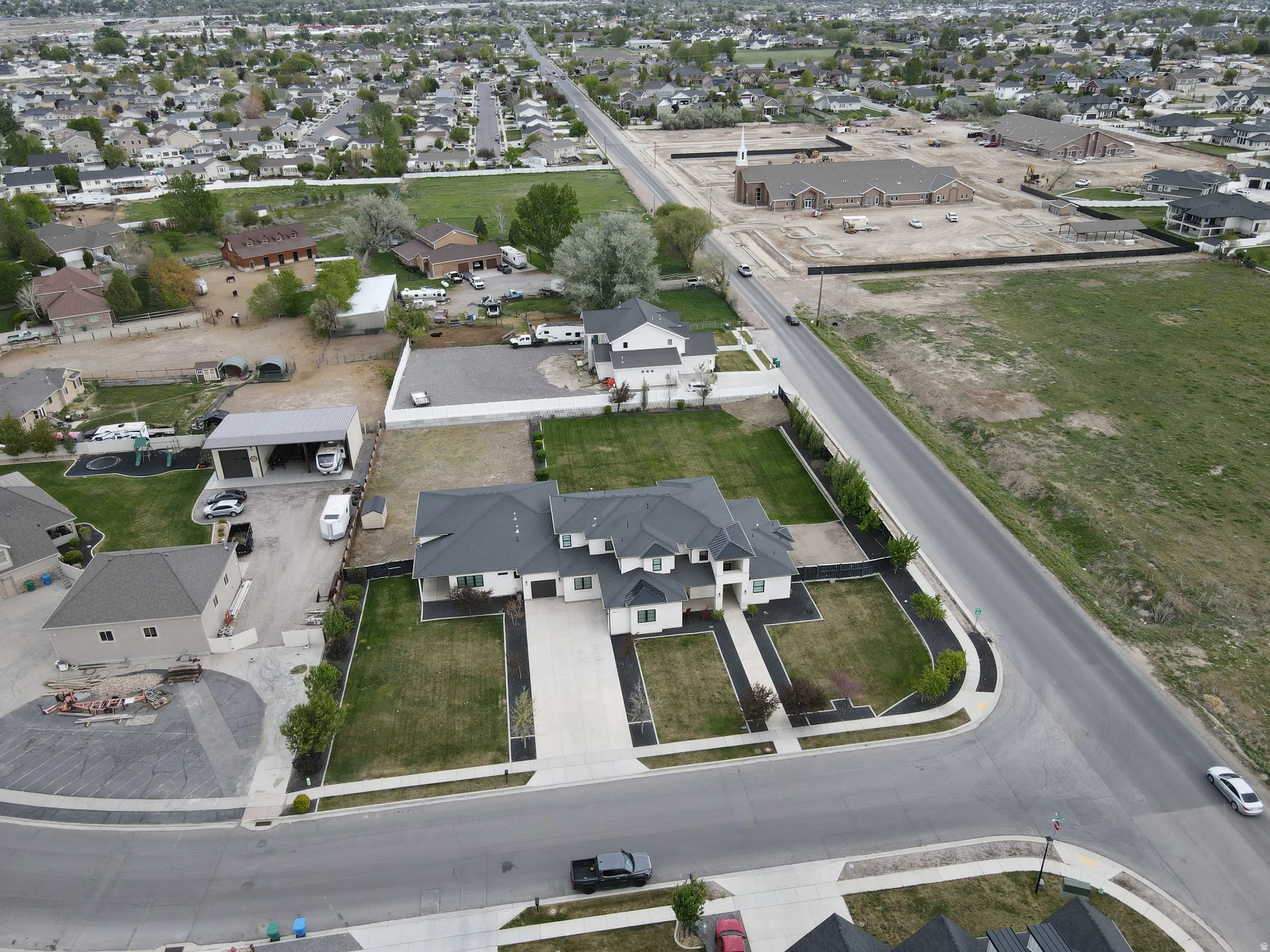 Expansive property featuring a large residence with a multi-car driveway, substantial grassy areas, and mature landscaping
