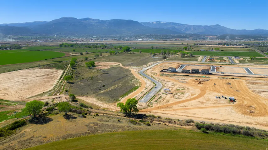 Expansive development opportunity featuring cleared land, established road infrastructure, and distant mountain scenery