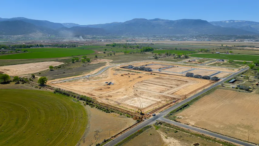 Aerial perspective of a large development site featuring graded lots and initial road infrastructure
