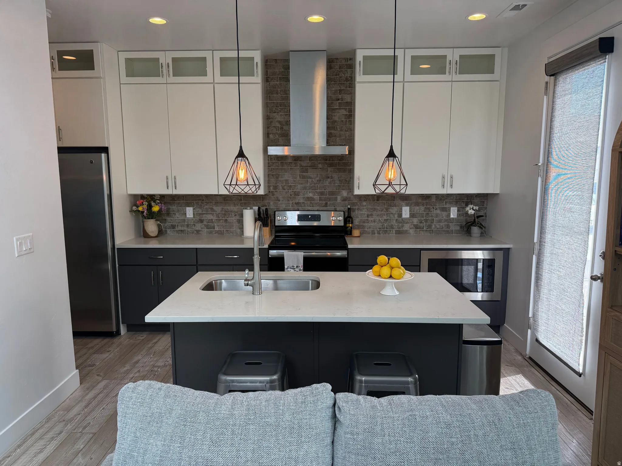 Modern kitchen featuring a central island with an integrated sink, quartz countertops, and stainless steel appliances