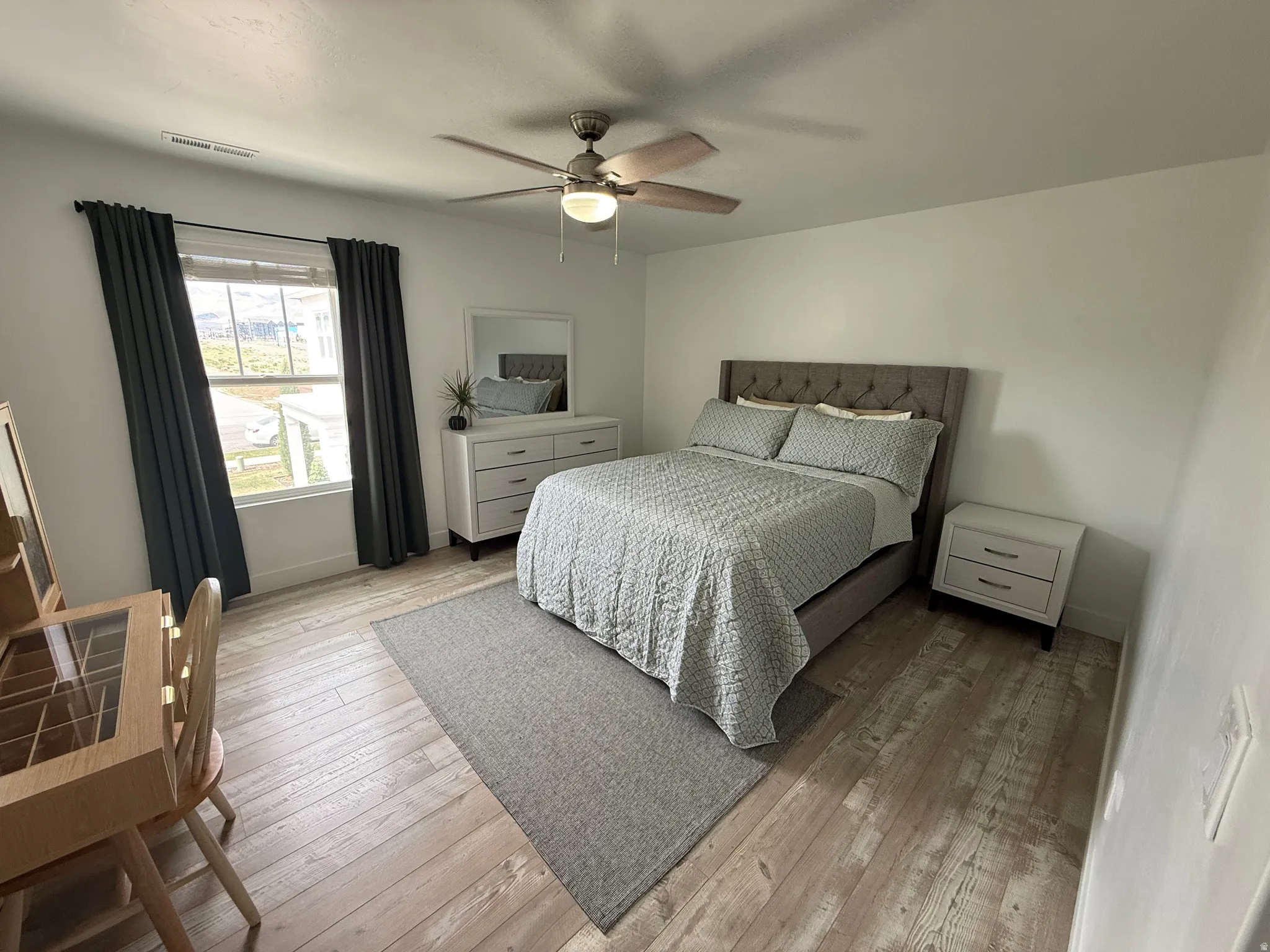 Bright room with light wood-finish flooring and a ceiling fan