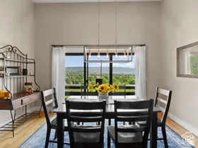 Dining area with light wood-finish flooring, featuring a linear pendant light fixture over a dining table