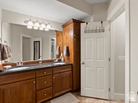 Bathroom featuring a dual vanity with a dark stone countertop, two undermount sinks, and wood cabinetry