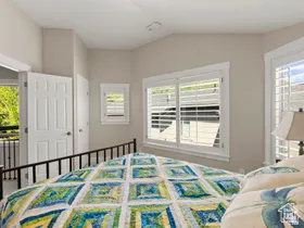 Bright room featuring multiple windows with louvered shutters, a white paneled door, and neutral wall tones