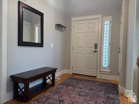 Foyer featuring light-toned walls, wood-finish flooring, a paneled entry door, and a sidelight window