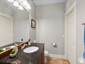 Vanity featuring a dark stone countertop with two undermount sinks, chrome faucets, and wood-finish cabinetry