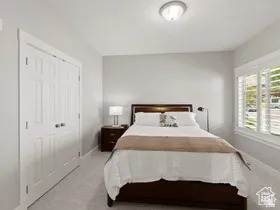 Bedroom featuring plush carpet, white walls, and a window with plantation shutters