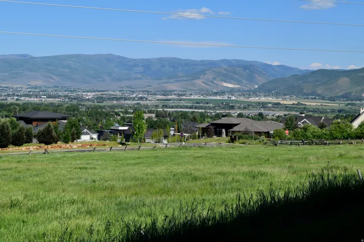 Expansive green field with distant mountain ranges and a valley landscape