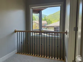 Interior landing with a wood handrail and black metal balusters with view of Master Bedroom Private Deck