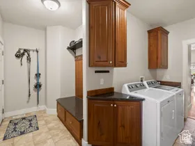Dedicated laundry area featuring a built-in bench with storage, dark wood-finish cabinetry, and a dark stone-finish countertop