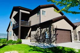 Multi-story exterior with stucco siding and stone accents, featuring a two-car garage with a panel door