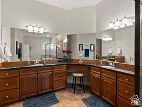 Expansive vanity area featuring dual integrated sinks, dark stone countertops, and extensive wood-finish cabinetry