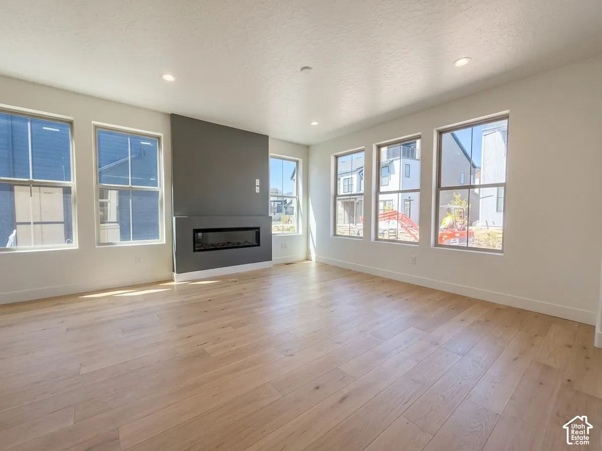 Recessed lighting, wood-finish flooring, multiple windows, a modern fireplace, and a contrasting accent wall