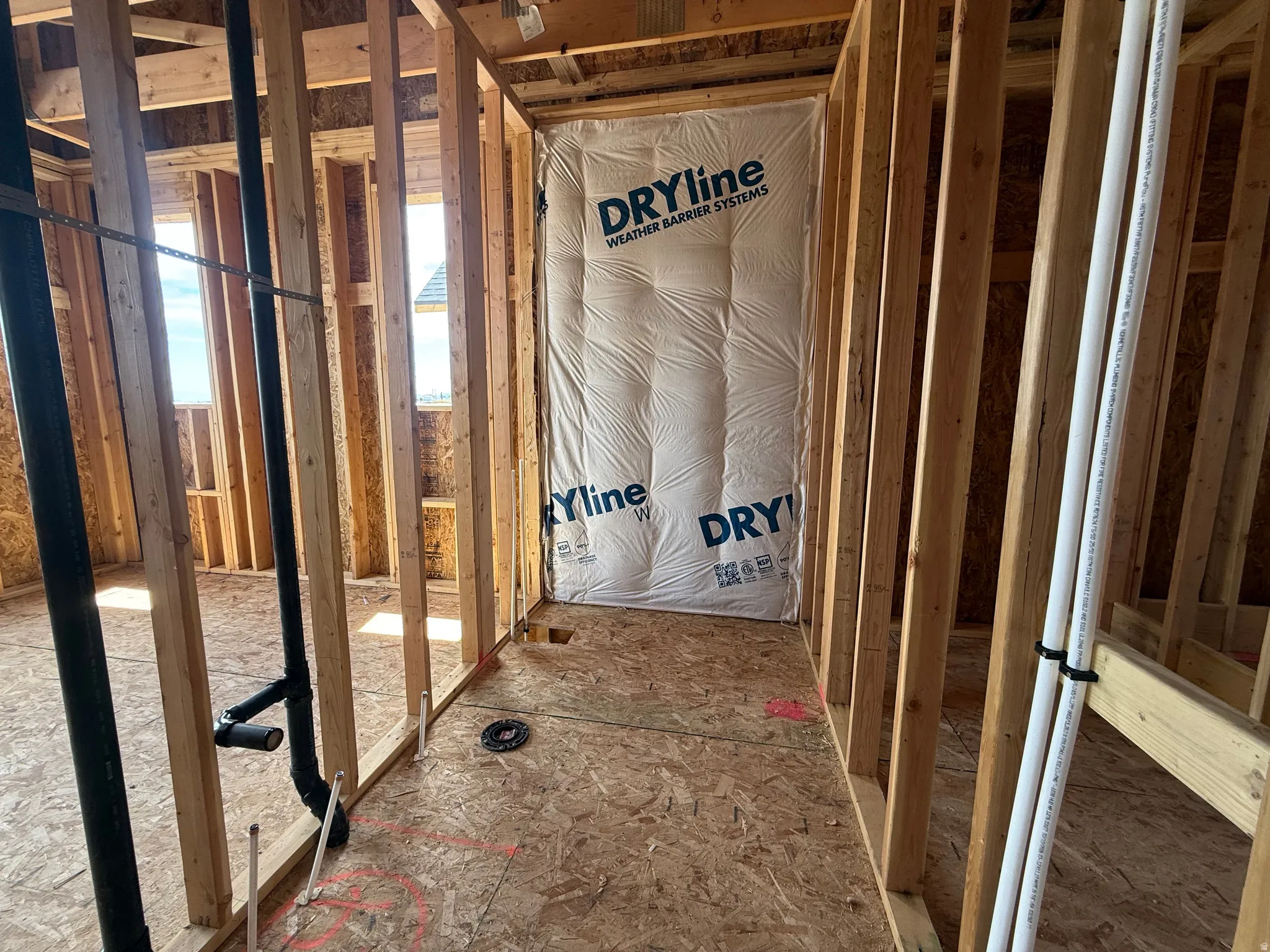Framed interior space featuring exposed wood studs, visible plumbing rough-ins, and subflooring, indicating new construction