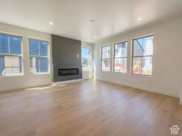 Recessed lighting, wood-finish flooring, multiple windows, a modern fireplace, and a contrasting accent wall