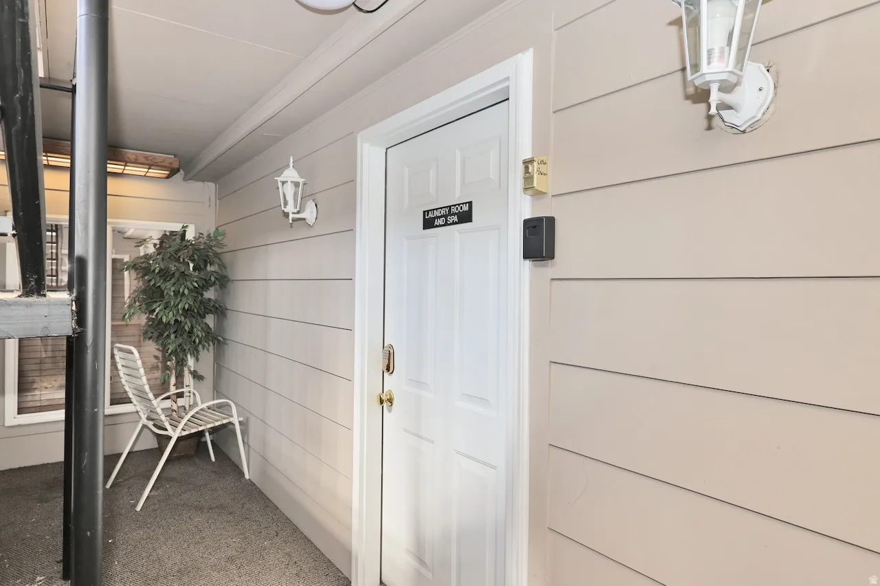 Entryway with horizontal siding and a paneled door featuring a brass handle