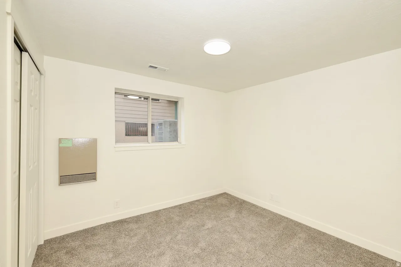 Interior space featuring light gray carpet, white walls, and a white ceiling with flush-mount lighting