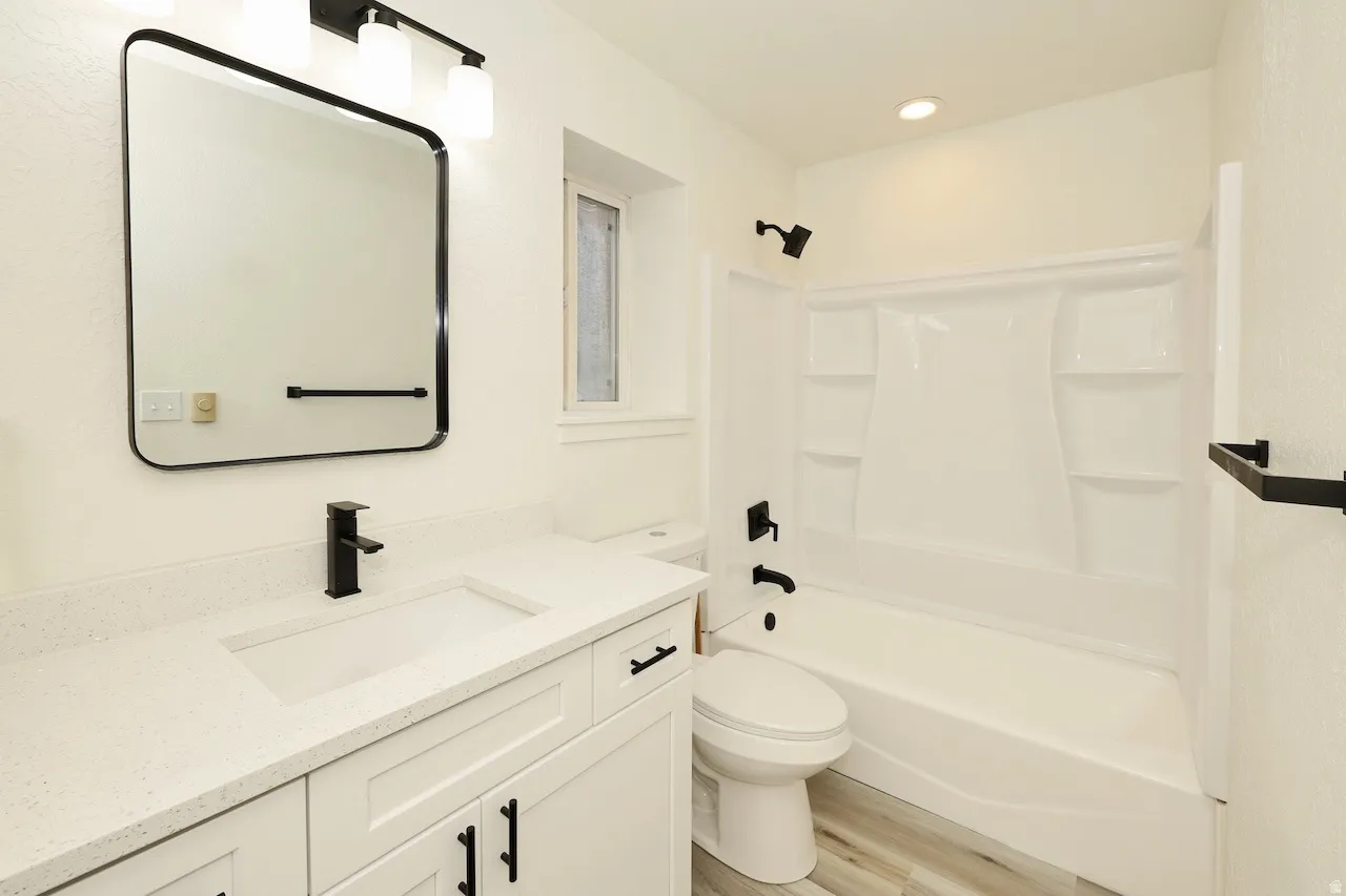 Bathroom featuring a white vanity with integrated sink, quartz-finish countertop, and matte black hardware