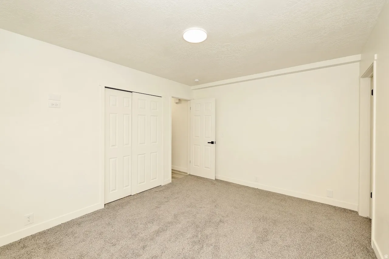 Room featuring neutral-toned walls, grey carpet flooring, and a flush-mount ceiling light fixture