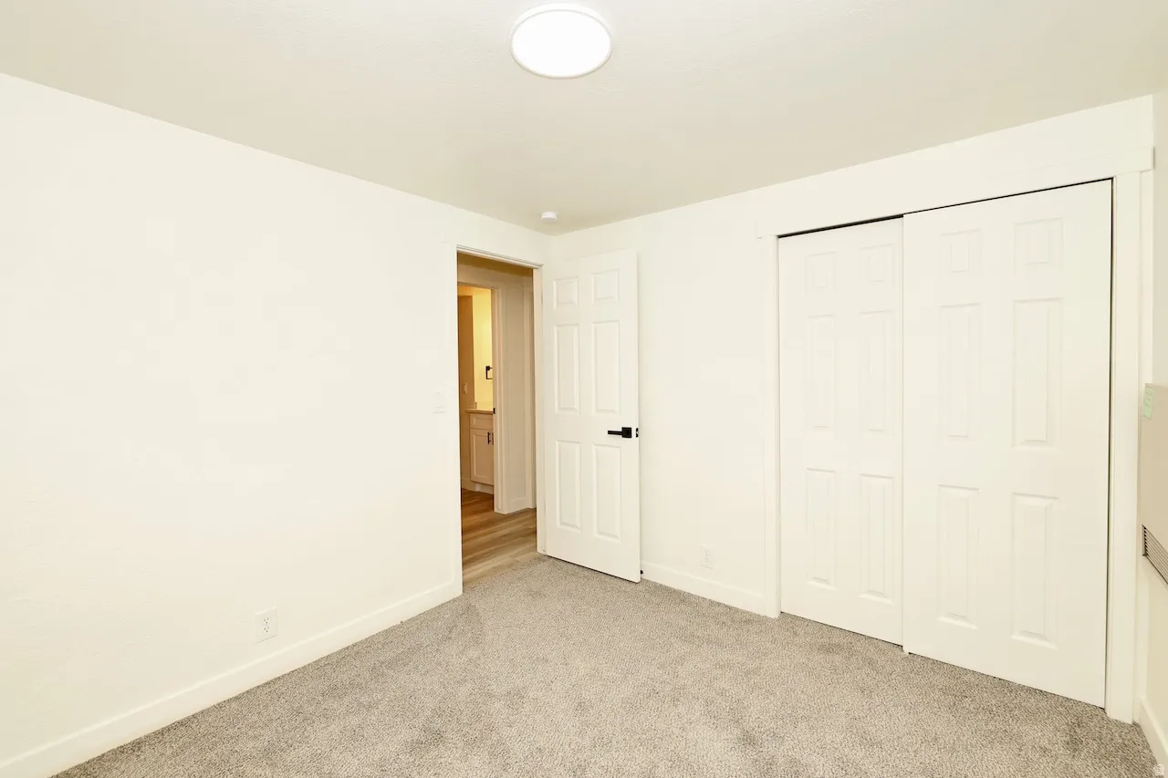 Neutral tone carpeted room with white walls, a white ceiling, and a flush mount ceiling light