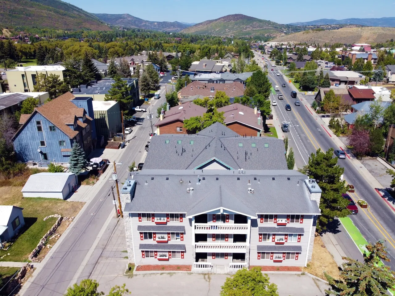 Multi-story property featuring light grey siding, red window shutters, and multiple balconies