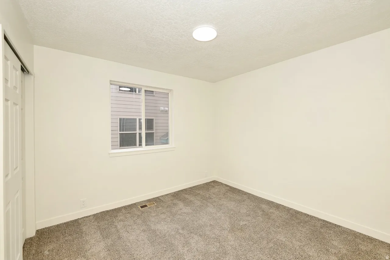 Carpeted room with a single window, a white trim baseboard, and a flush-mount ceiling light fixture