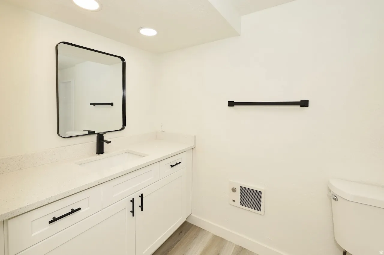Bathroom vanity featuring a light-toned countertop with an integrated sink, white cabinetry with matte black hardware, and a framed rectangular mirror