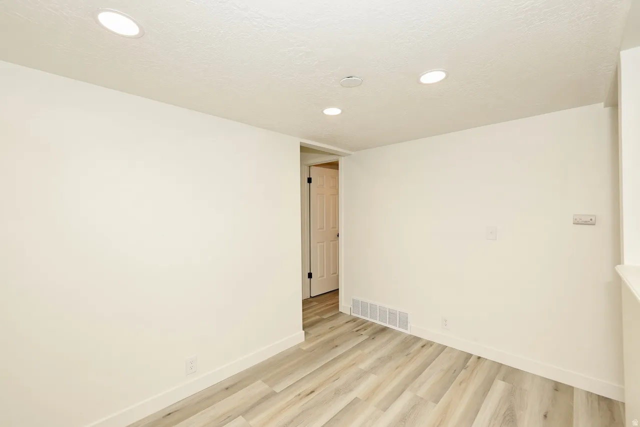 Spacious room featuring wood-finish flooring and recessed ceiling lighting