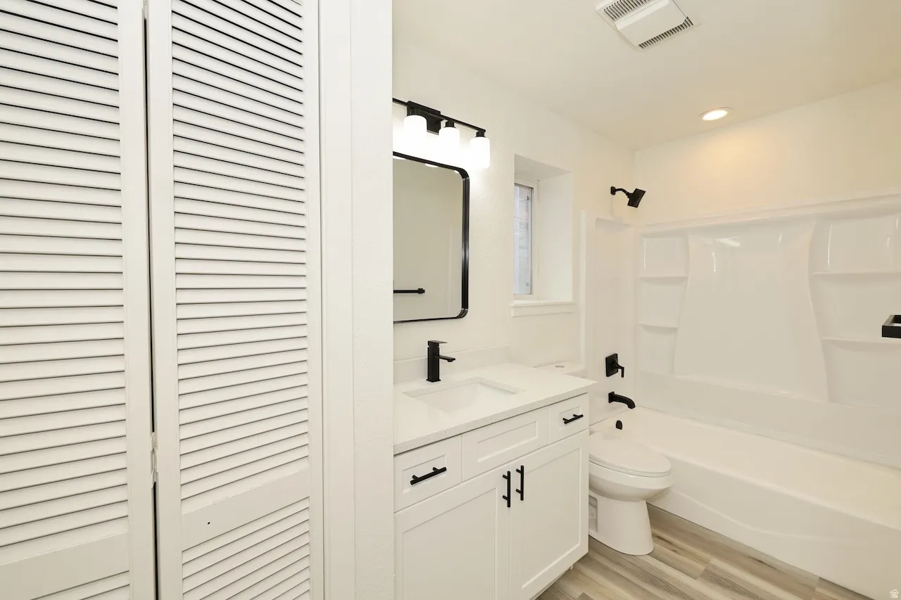 Bathroom featuring a white vanity with an integrated sink, quartz-finish countertop, and matte black fixtures
