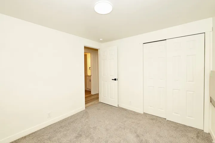 Neutral tone carpeted room with white walls, a white ceiling, and a flush mount ceiling light