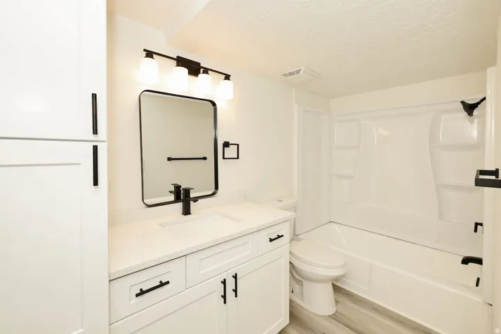 Contemporary bathroom featuring a white vanity with a light-colored countertop, a rectangular black-framed mirror, and a modern black faucet
