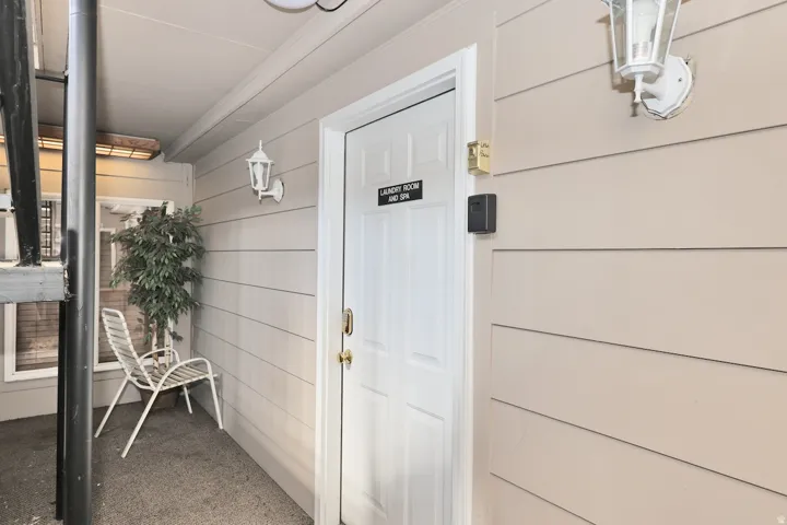 Entryway with horizontal siding and a paneled door featuring a brass handle
