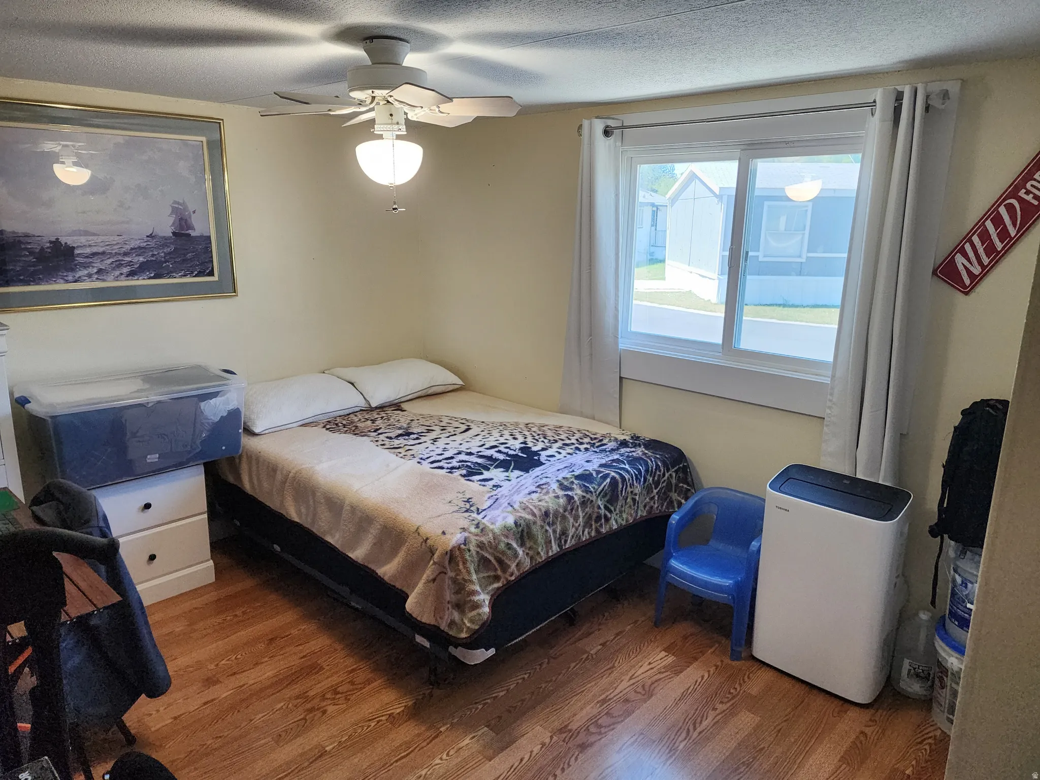 Room featuring wood-finish flooring, light-colored walls, and a ceiling fan with integrated lighting
