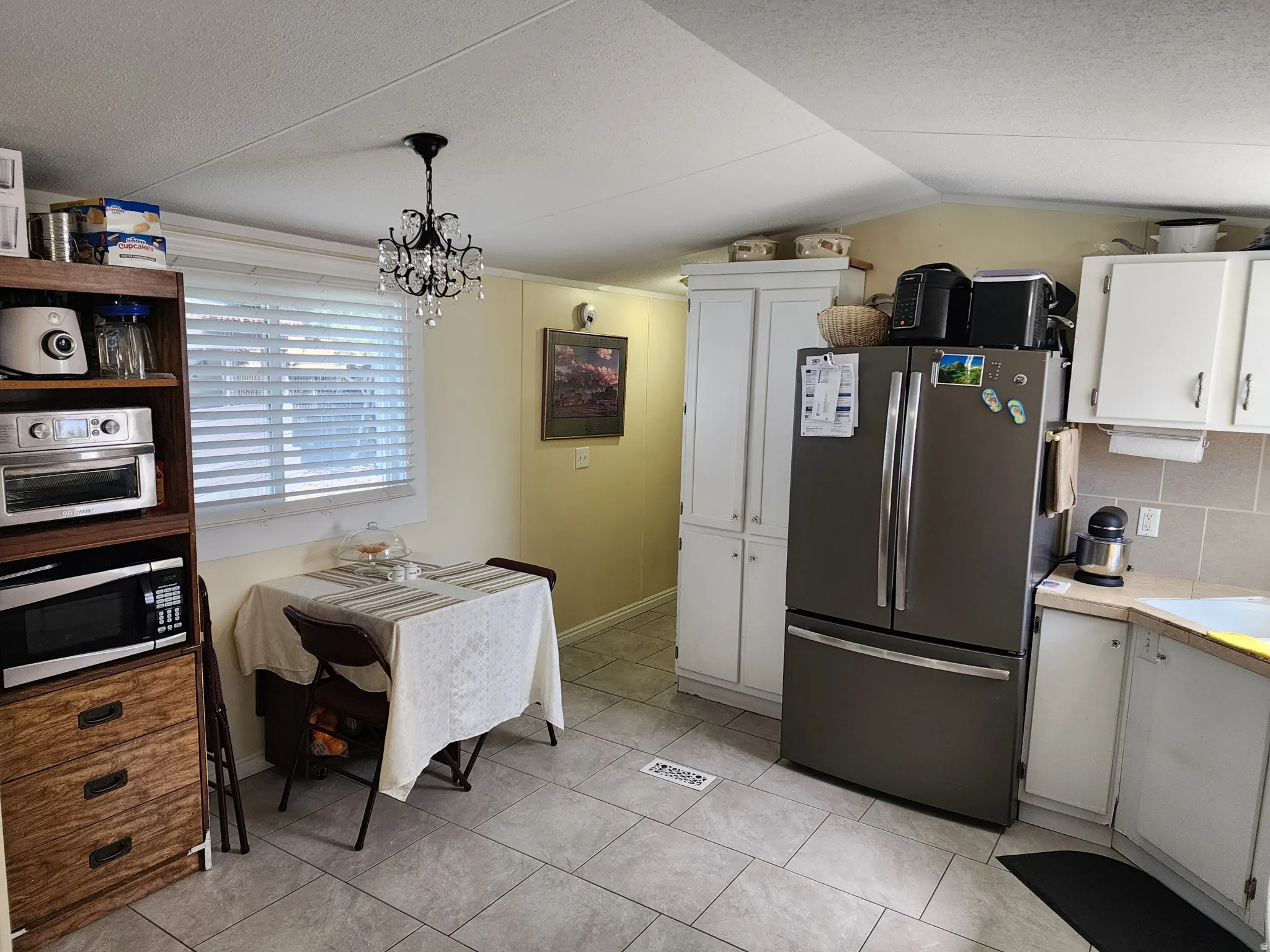 Kitchen area featuring neutral-toned tile flooring, light-toned walls, and white cabinetry
