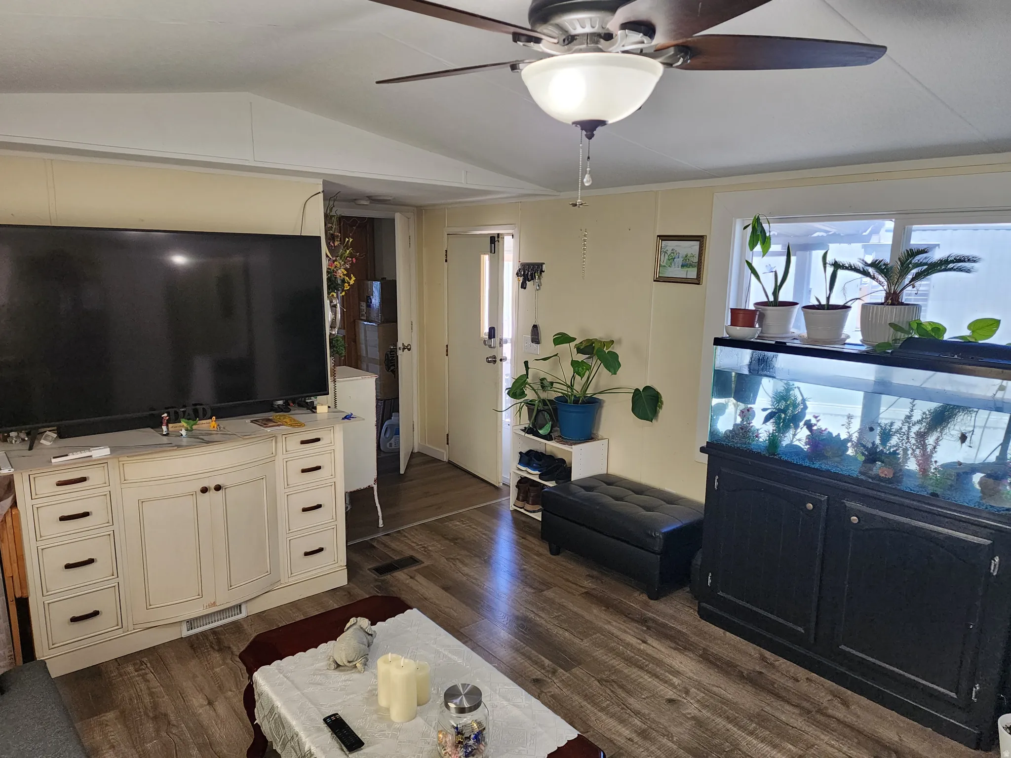 Spacious living area featuring wood-finish flooring, a ceiling fan with integrated lighting, and neutral wall tones