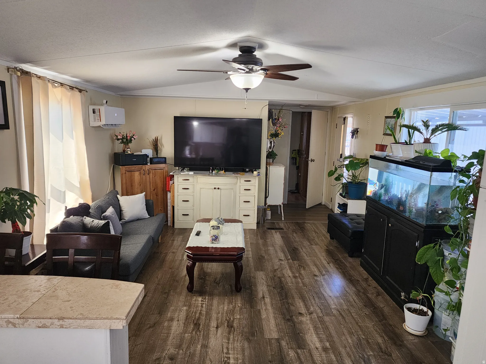 Living area featuring wood-finish flooring, a ceiling fan with integrated lighting, and neutral wall tones