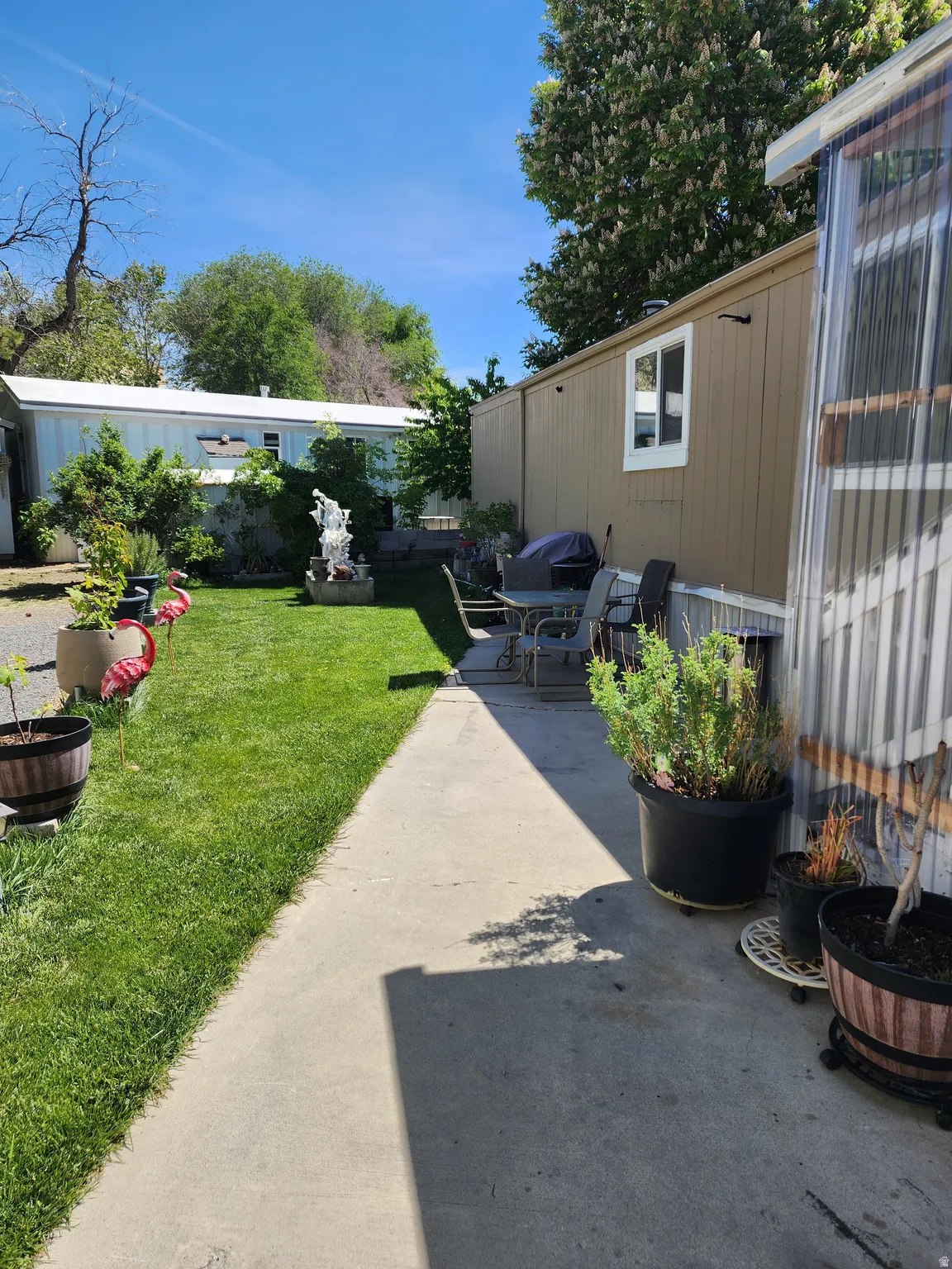 Concrete patio area with a privacy screen, extending to a manicured lawn