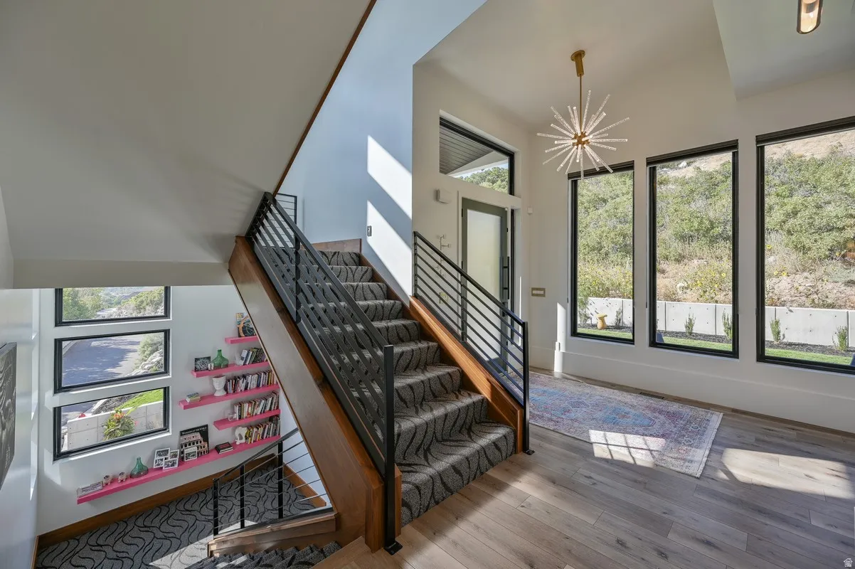 Two-story foyer featuring a contemporary chandelier, wood-finish flooring, and a staircase with metal railings
