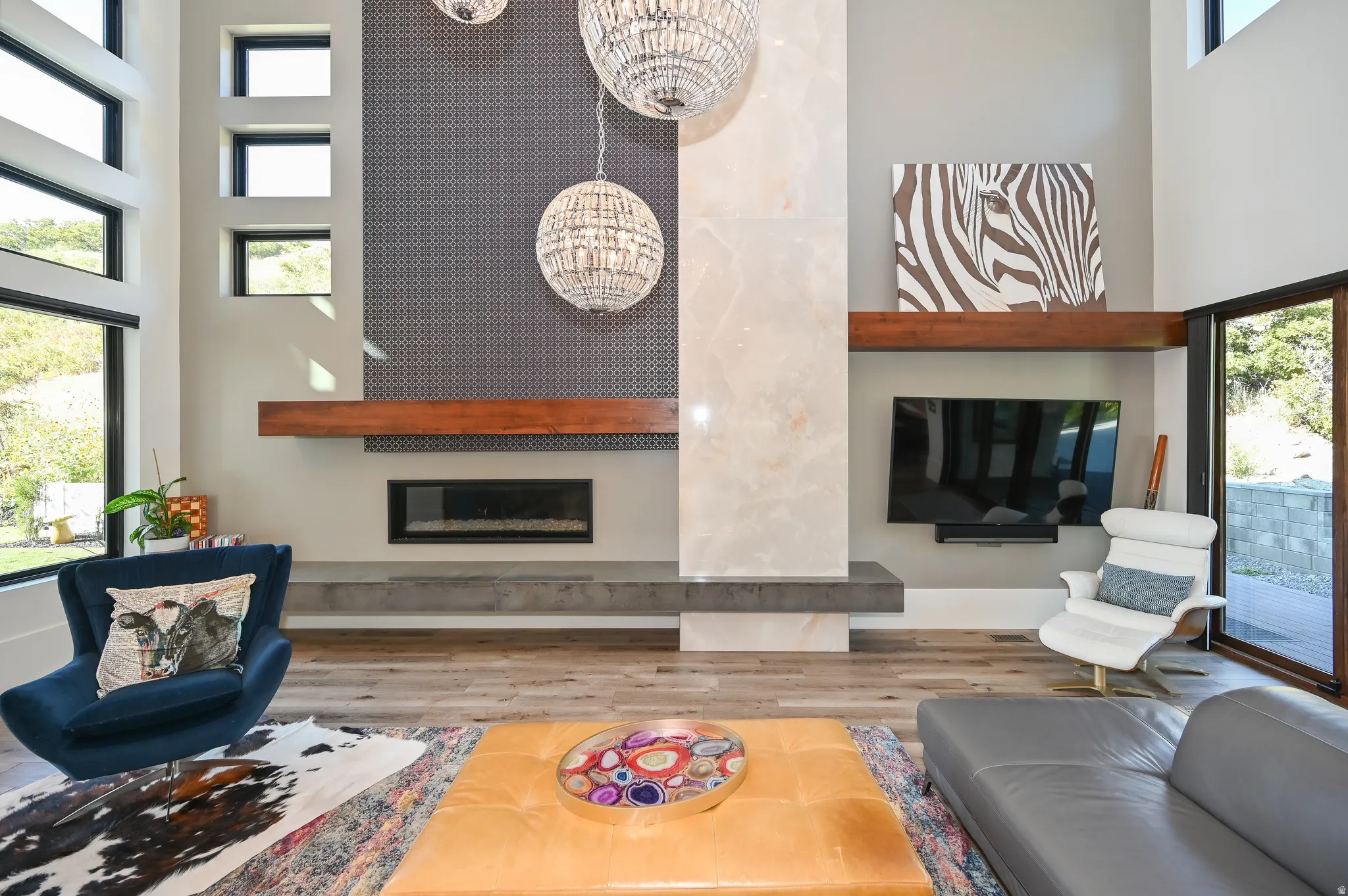 Spacious interior featuring high ceilings, large multi-pane windows, a linear fireplace, contemporary light fixtures, and wood-finish flooring