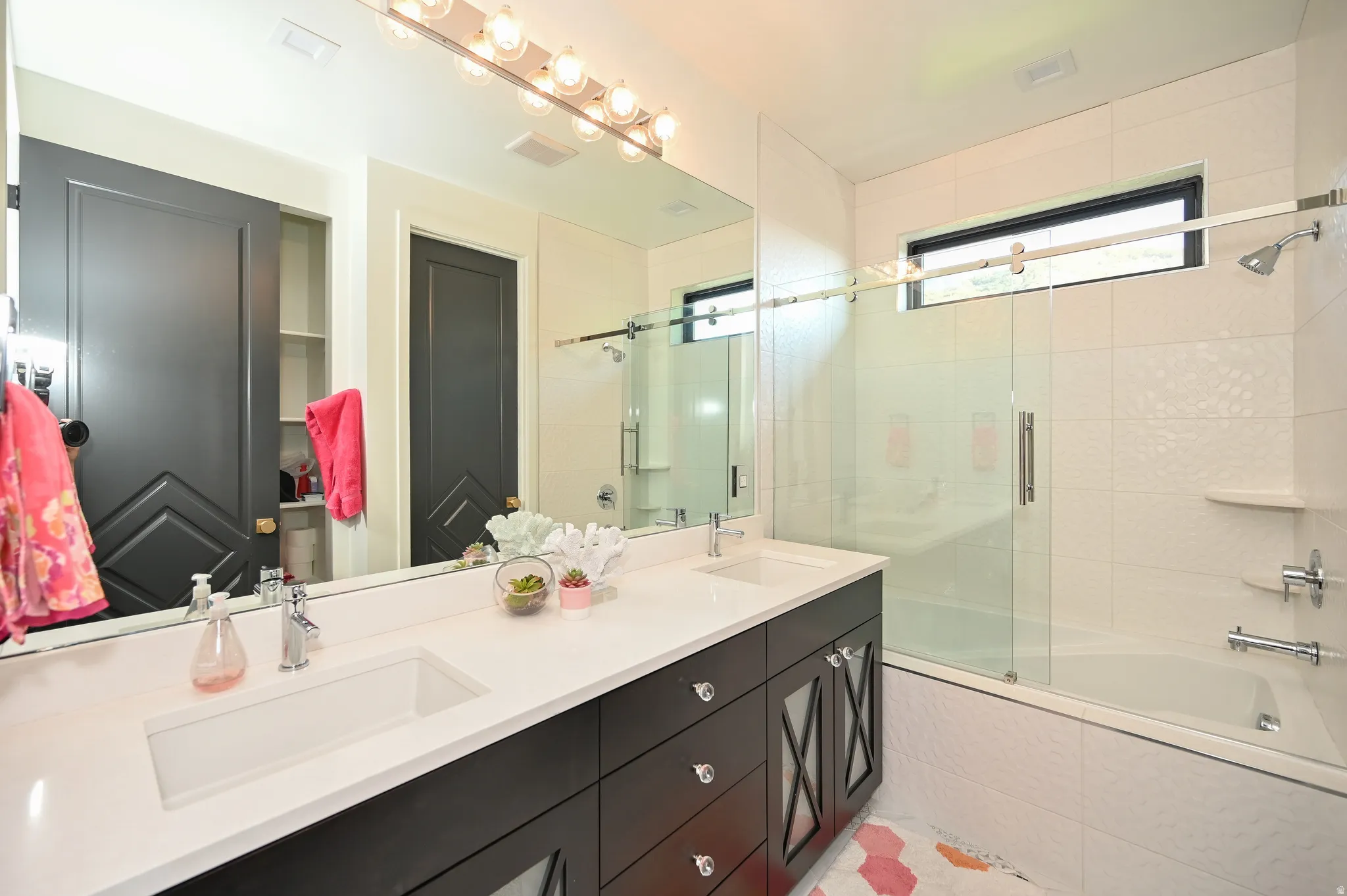 Dual integrated sinks set within an expansive white countertop and dark wood-finish vanity