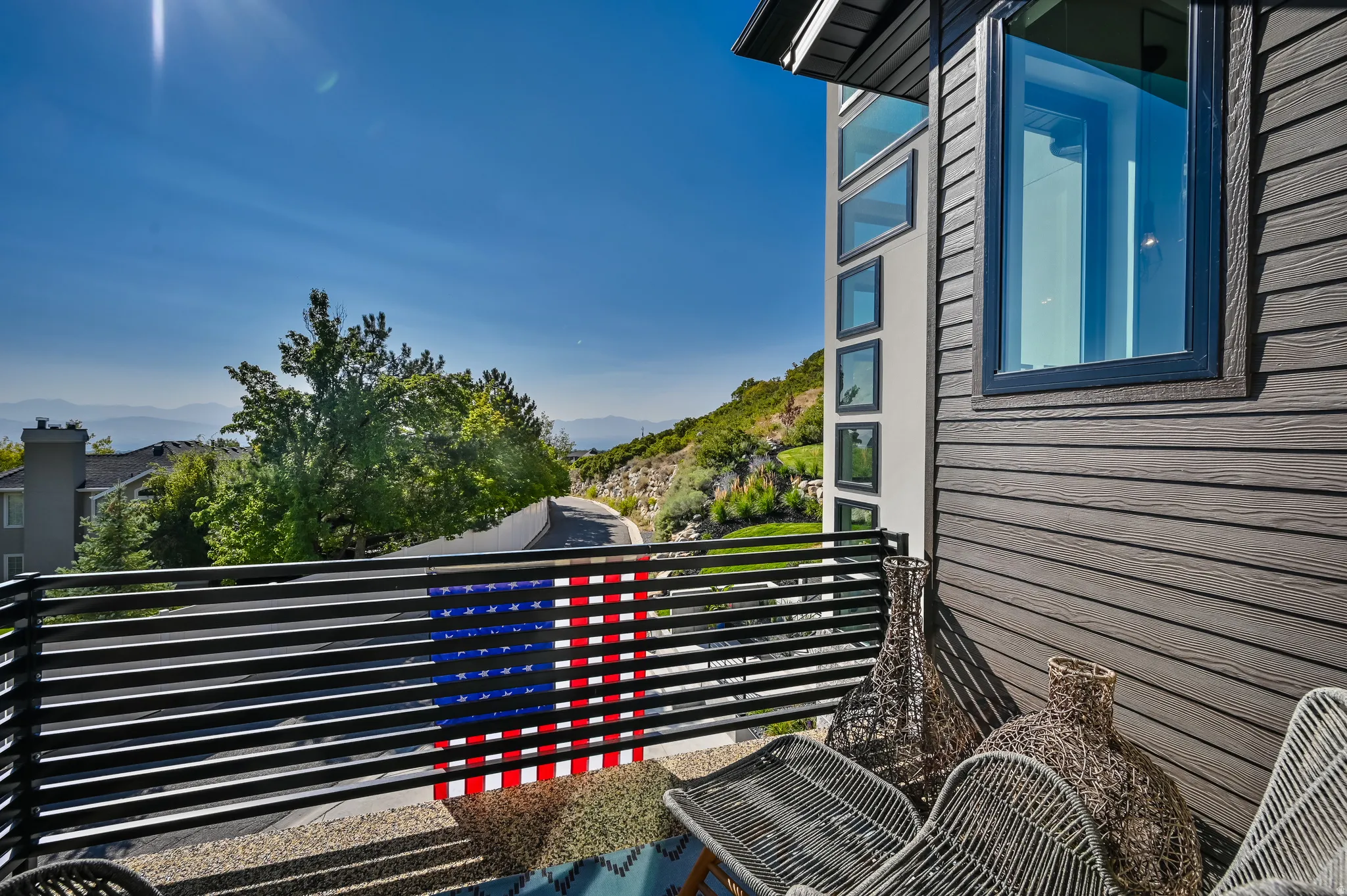 Exterior balcony featuring horizontal metal railings and a textured wall with multiple windows