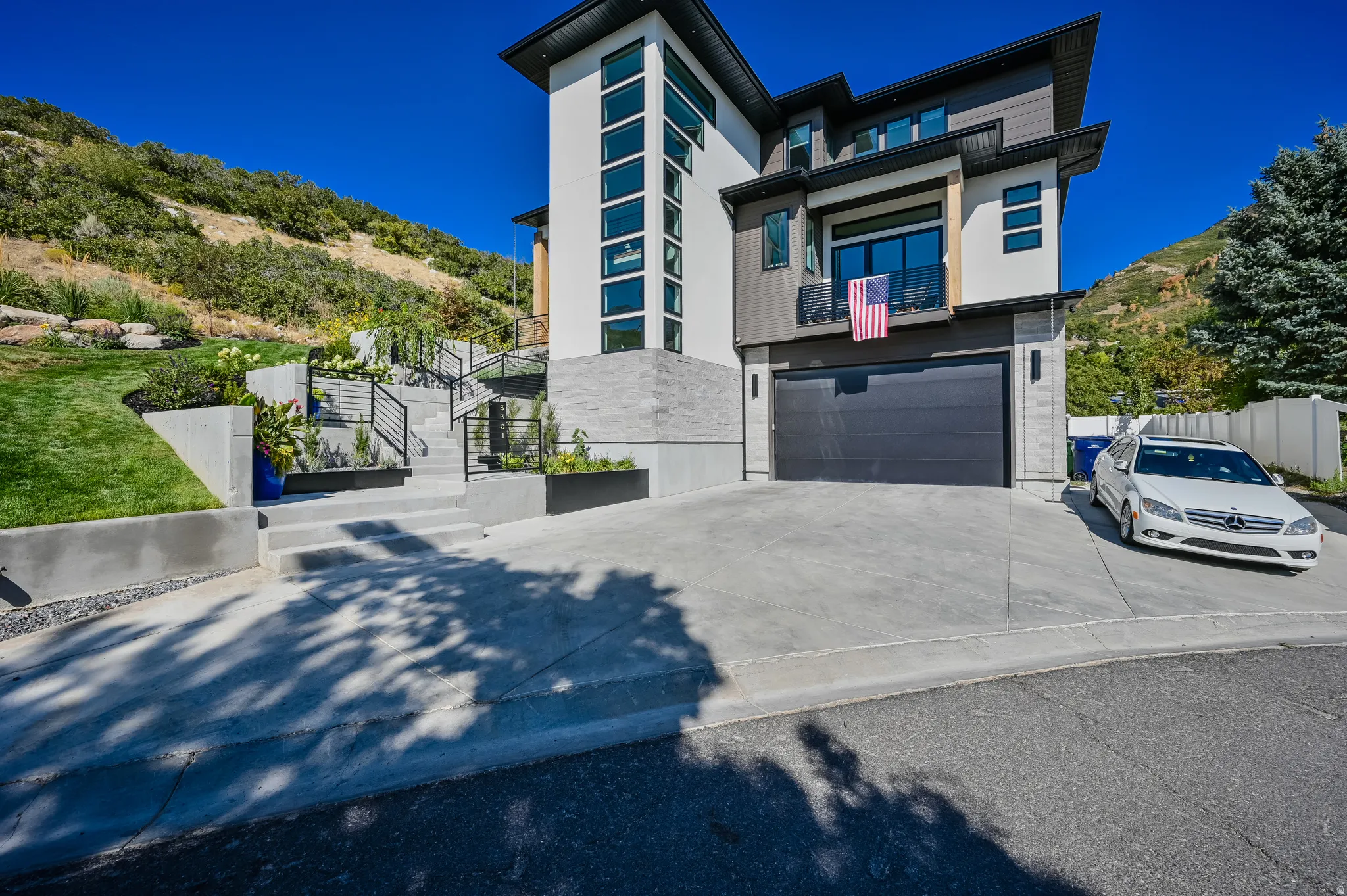Contemporary multi-level residence featuring a dark-paneled garage door, a second-story balcony with dark railings, and prominent vertical window arrays