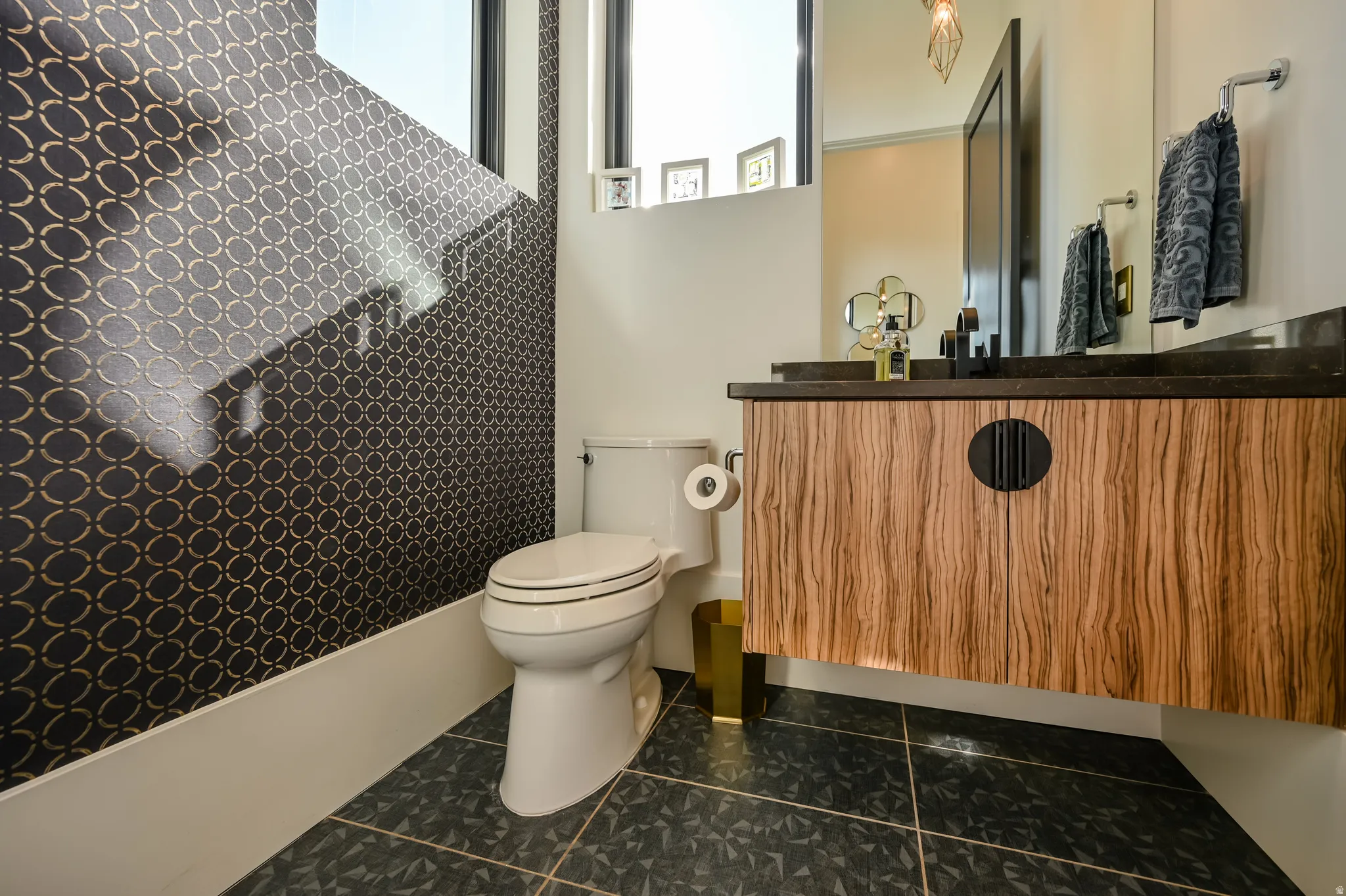 Floating wood-finish vanity with a dark countertop and matte black faucet