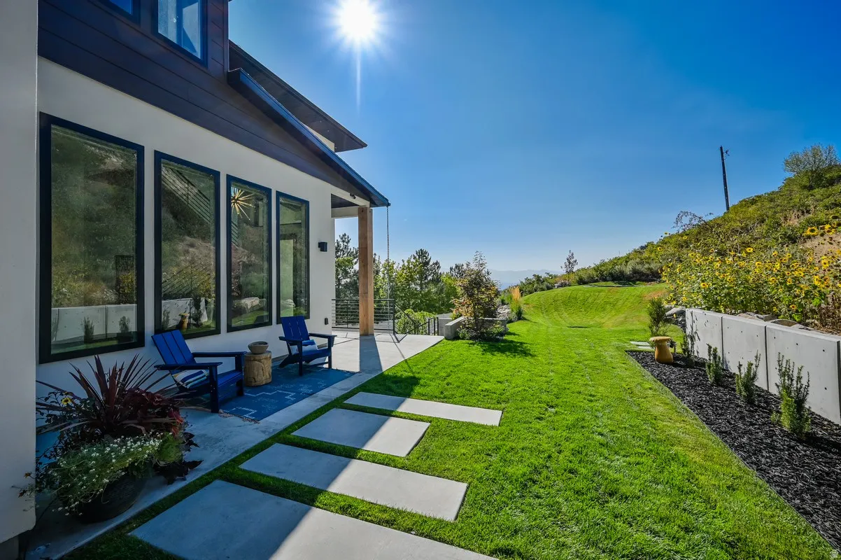 Outdoor concrete patio featuring a series of rectangular stepping stones set in a lush green lawn