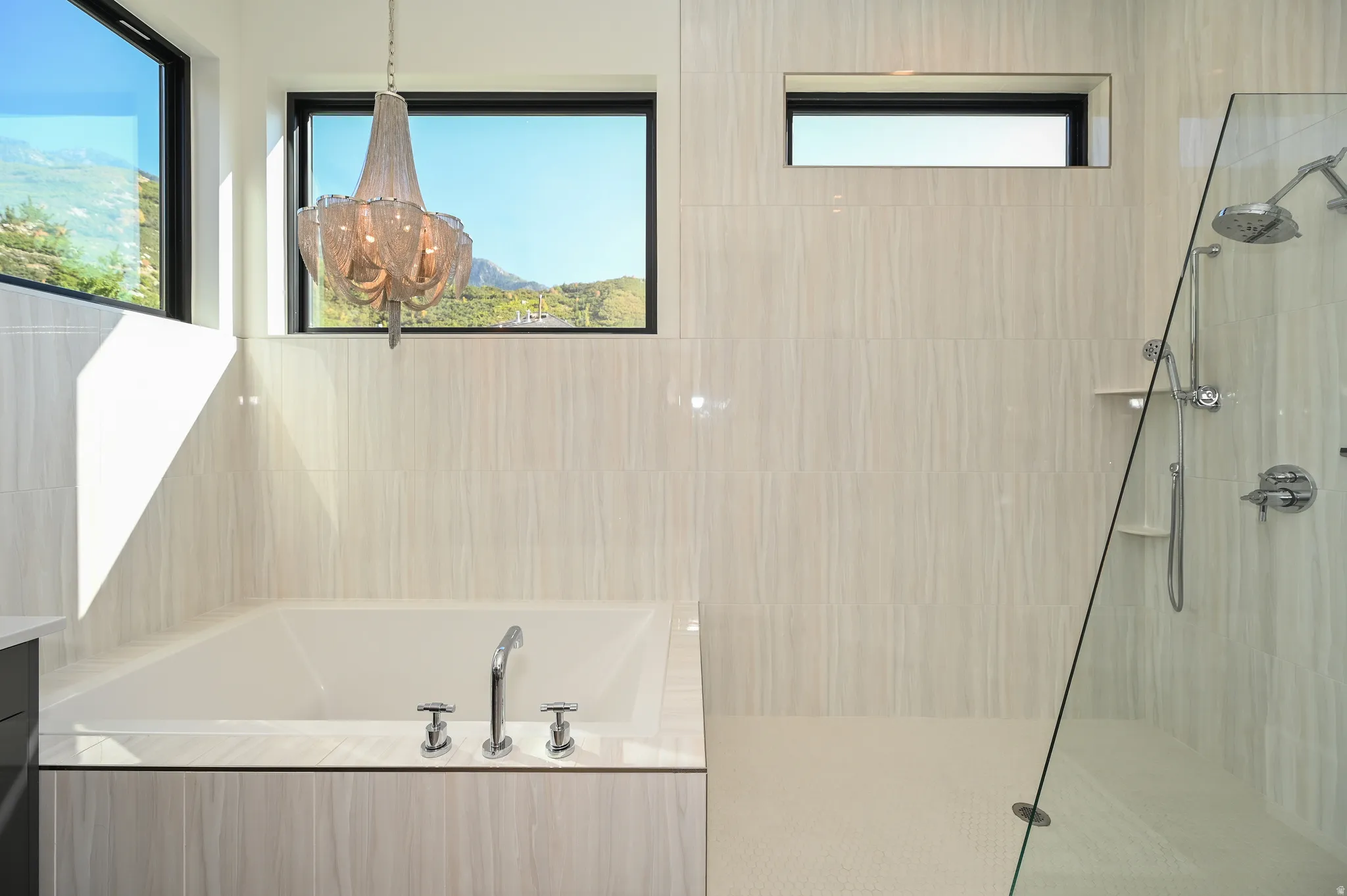 Soaking tub with deck-mounted chrome fixtures, set against light-toned wall tiling