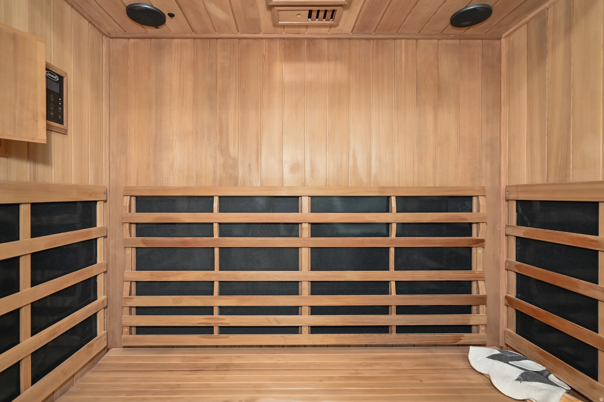 Wood-paneled sauna featuring built-in benches, integrated speakers, and a digital control panel