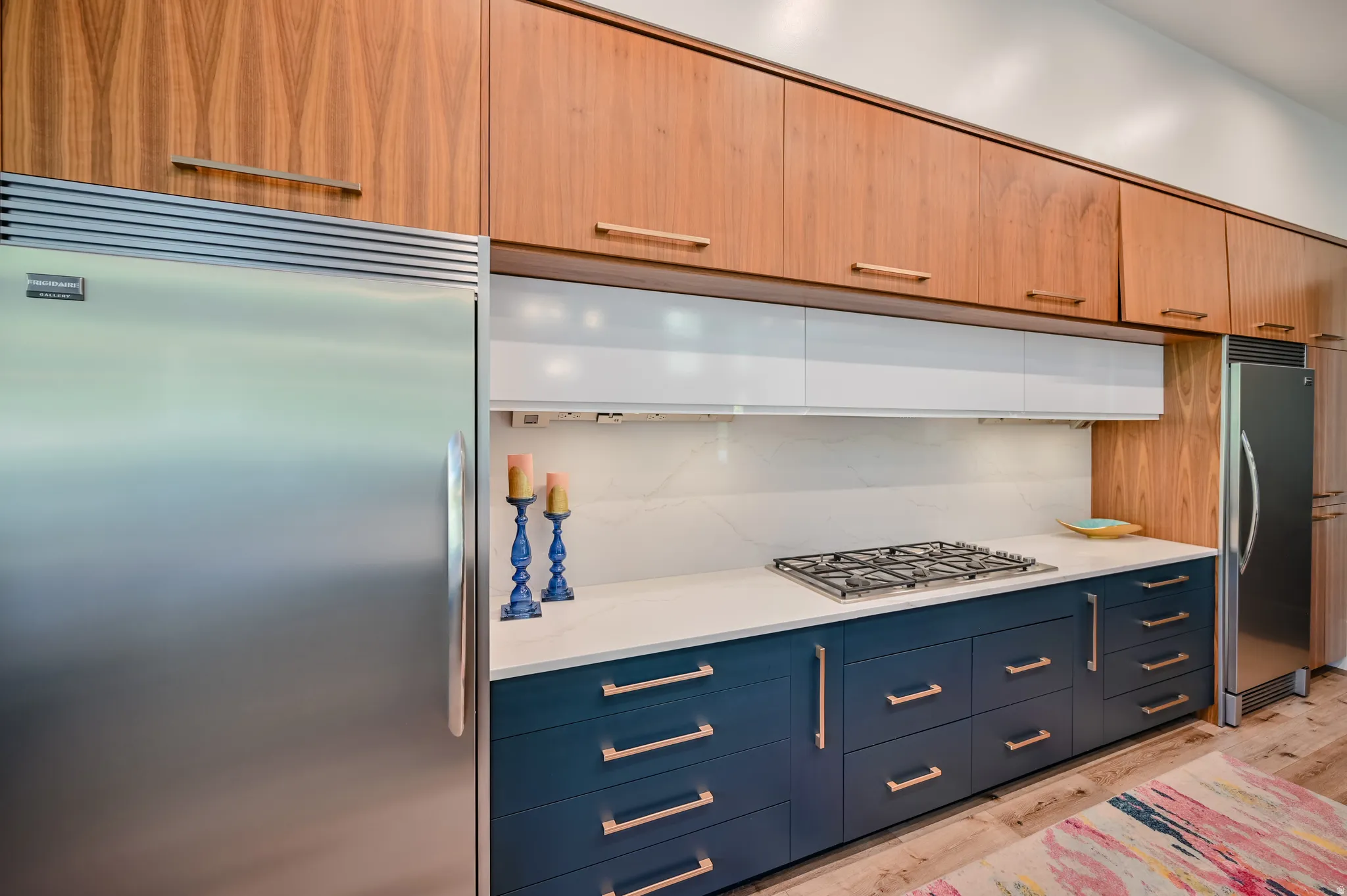 Modern kitchen featuring wood-finish upper cabinetry, integrated stainless steel appliances, and a gas cooktop