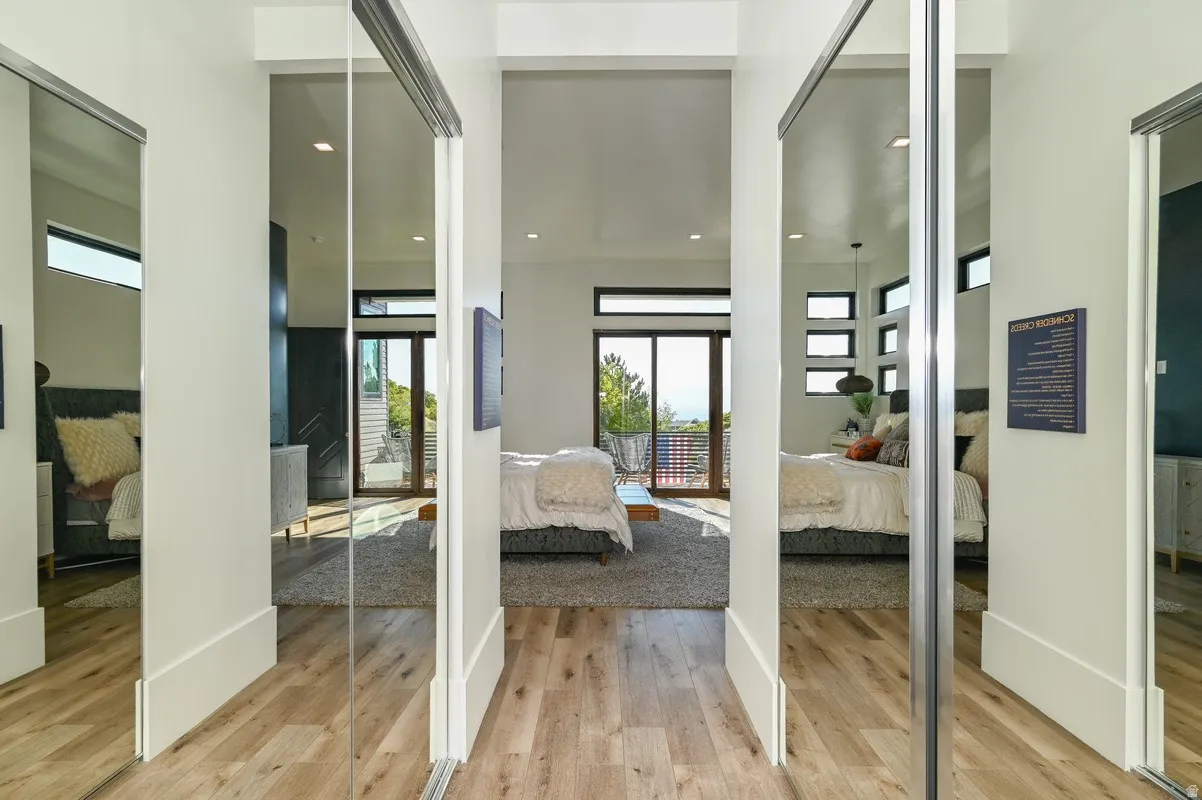 Hallway featuring wood-finish flooring, mirrored sliding closet doors, and recessed lighting