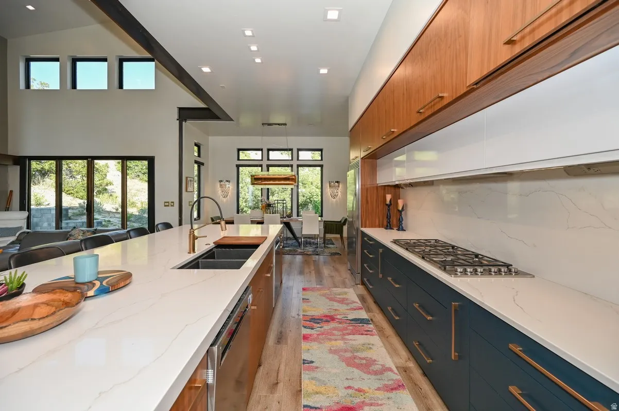 Modern kitchen featuring a gas cooktop, integrated double sink, white countertops, and wood-finish flooring