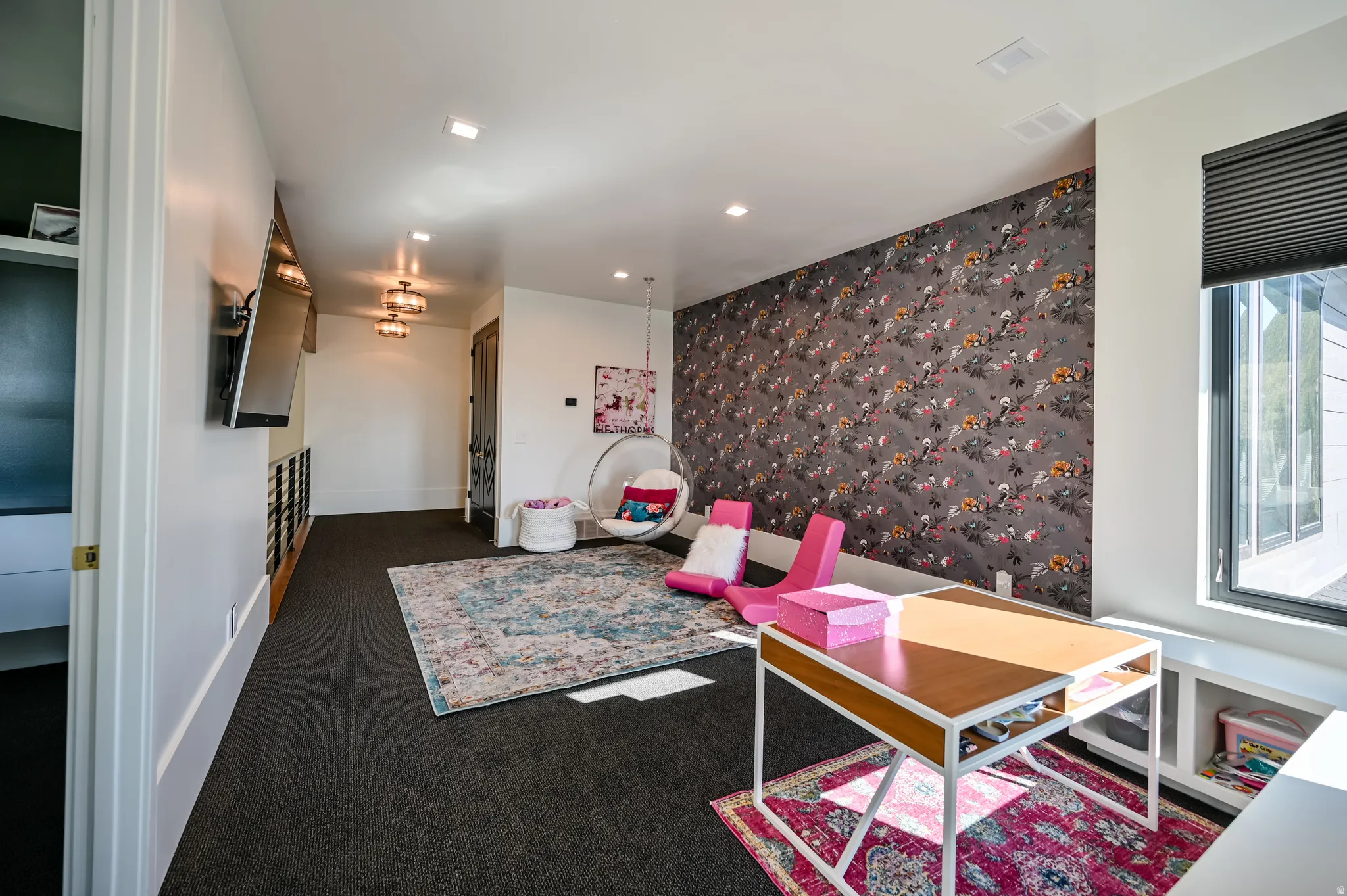 Spacious room featuring dark carpeting, a patterned accent wall, recessed lighting, and a large window with blinds